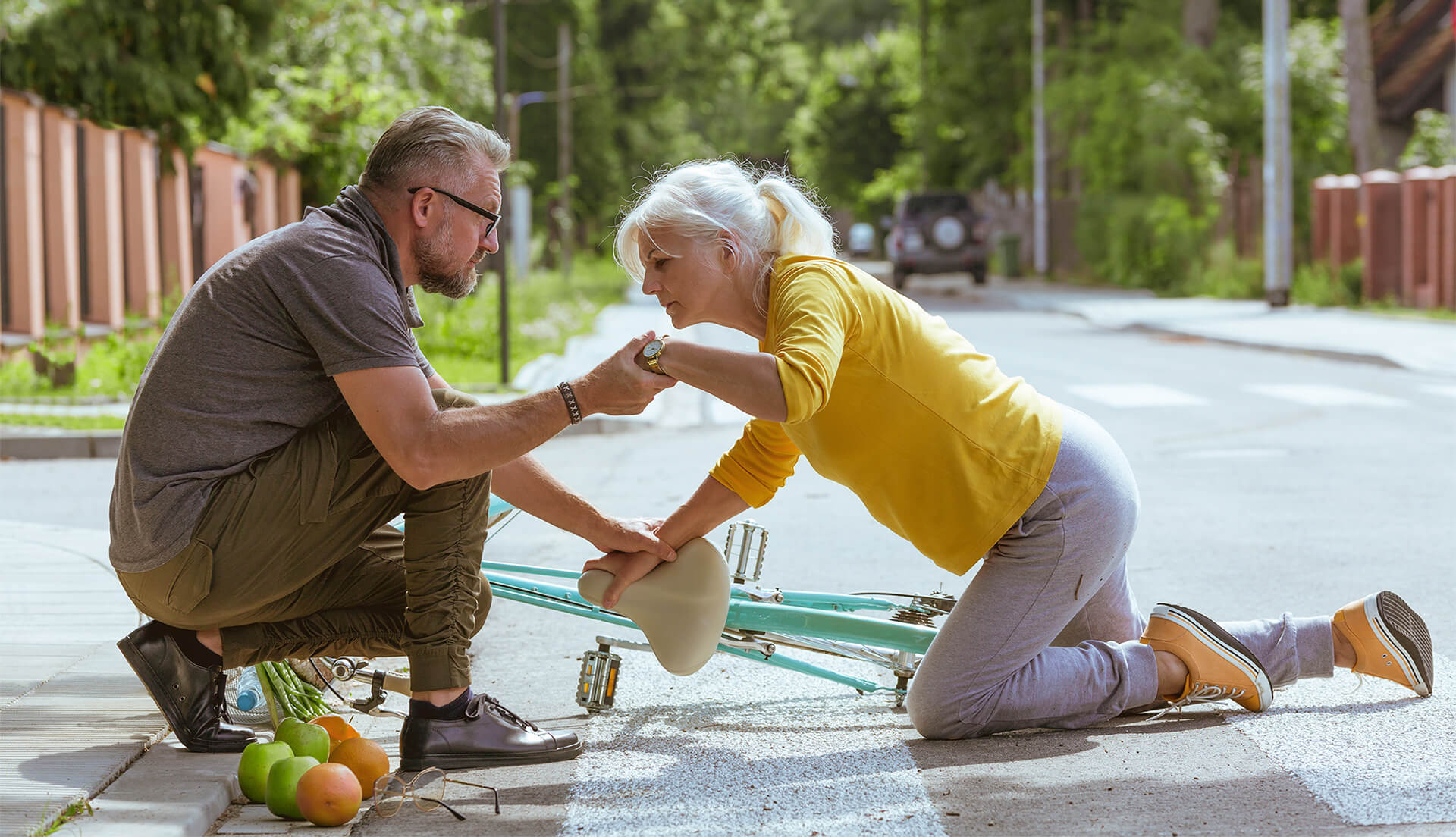 Un homme aide un femme à se relever après une chute à vélo dans la rue